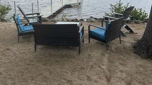 A lakeside seating area with chairs and a dock extending into the water. - Lakefront home on Ossipee Lake with dock and gorgeous views  (Ossipee)
