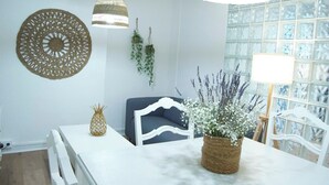 A dining area with a white table, a pineapple centerpiece, a woven basket with flowers, a blue sofa, and hanging plants. - ABASTOS "Ferrol" Apartment (Ferrol)