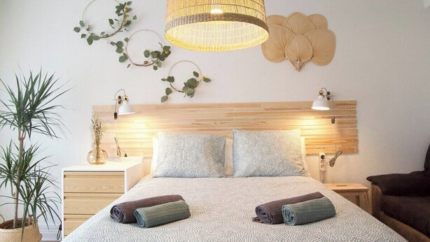 A well-lit bedroom with a wooden headboard, two bedside tables, a large bed with rolled towels, and decorative wall art. - ABASTOS "Ferrol" Apartment (Ferrol)