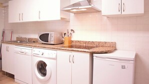 A kitchen with white cabinets, a microwave, a toaster, and a washing machine. - ABASTOS "Ferrol" Apartment (Ferrol)