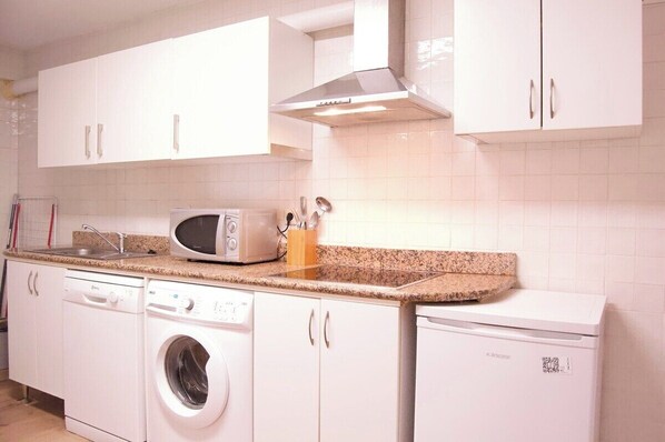 A kitchen with white cabinets, a microwave, a toaster, and a washing machine.