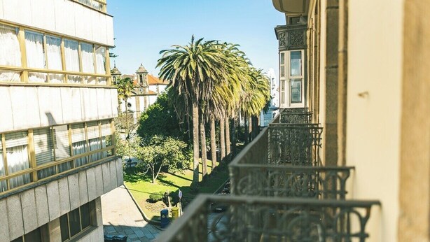 Une rue étroite en milieu urbain, avec un palmier et un immeuble doté d’un balcon.