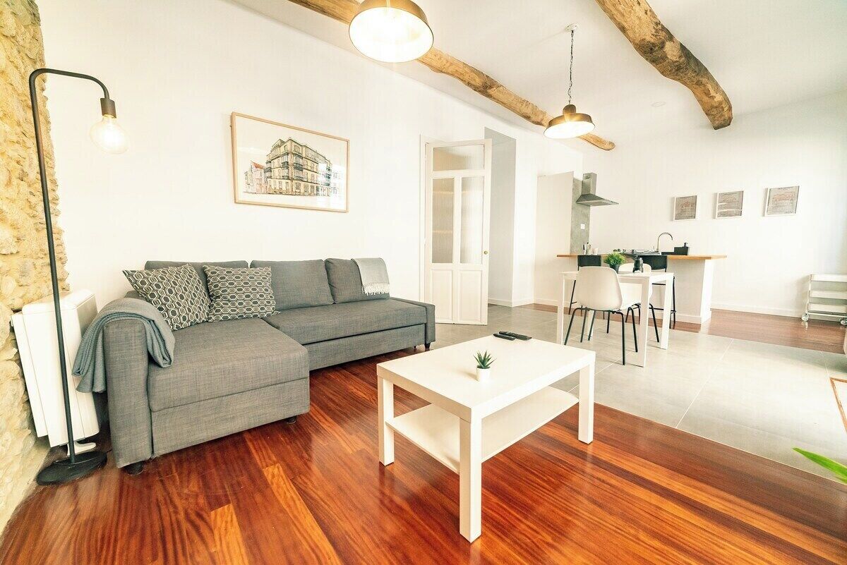 A modern living room with a grey sofa, a white coffee table, and wooden flooring.