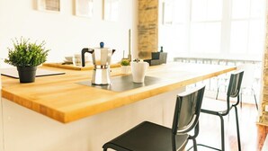 Une cuisine moderne avec un plan de travail en bois, une machine à café, une plante en pot et un mur d’accent en pierre.