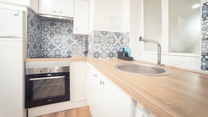 A kitchen with white cabinets, a stainless steel oven, a sink, and patterned backsplash tiles. - Apartment Sol "Ferrol". (Ferrol)