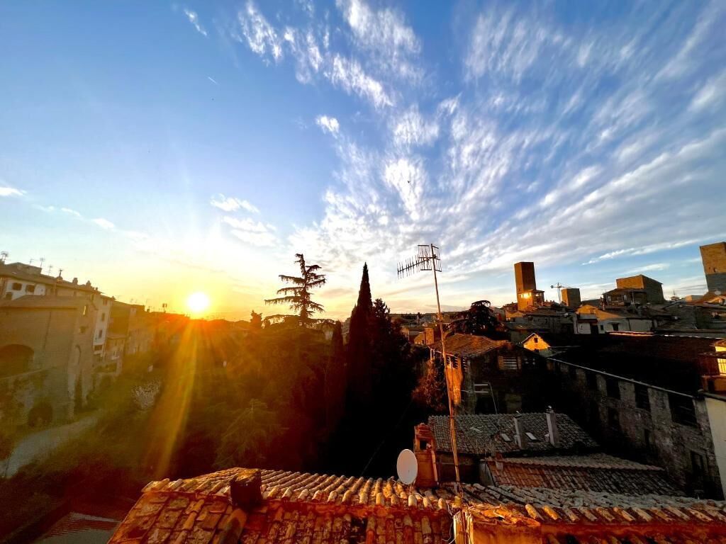 A cityscape at sunset with a clear sky, buildings, and a prominent tower.