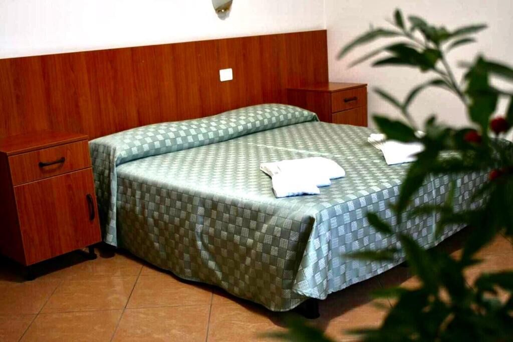 A single bed with a checkered bedspread in a room with wooden headboard and nightstands.