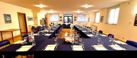 A conference room with long tables set for a meeting, equipped with water bottles, glasses, and notepads.