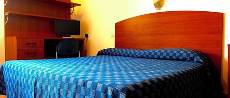 A bedroom with a bed, a desk, a chair, and a television.