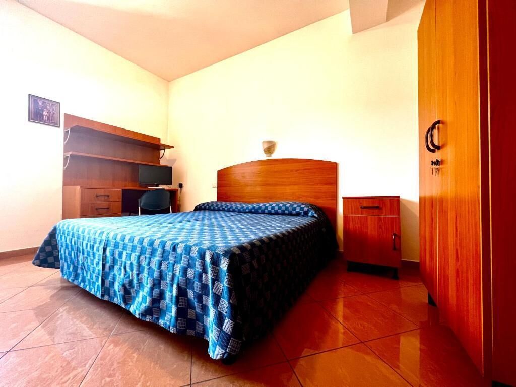 Un dormitorio con cama, un armario de madera, un escritorio con silla y televisor.