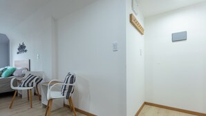 A room with a bed, two chairs, a small table, and a wall-mounted shelf. - Gente del Sur - Finisterre (Ushuaia)