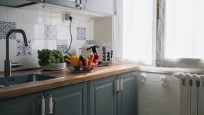 A kitchen with a wooden countertop, a sink, a bowl of vegetables, and a window with curtains. - [La terrazza di Chiavari] (Chiavari)