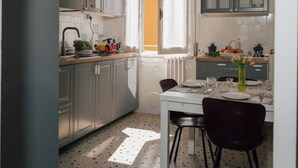 A compact kitchen with a dining area, featuring a chandelier, cabinets, and a window with curtains. - [La terrazza di Chiavari] (Chiavari)