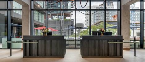 A modern reception area with two reception desks, large windows, and a view of surrounding buildings.