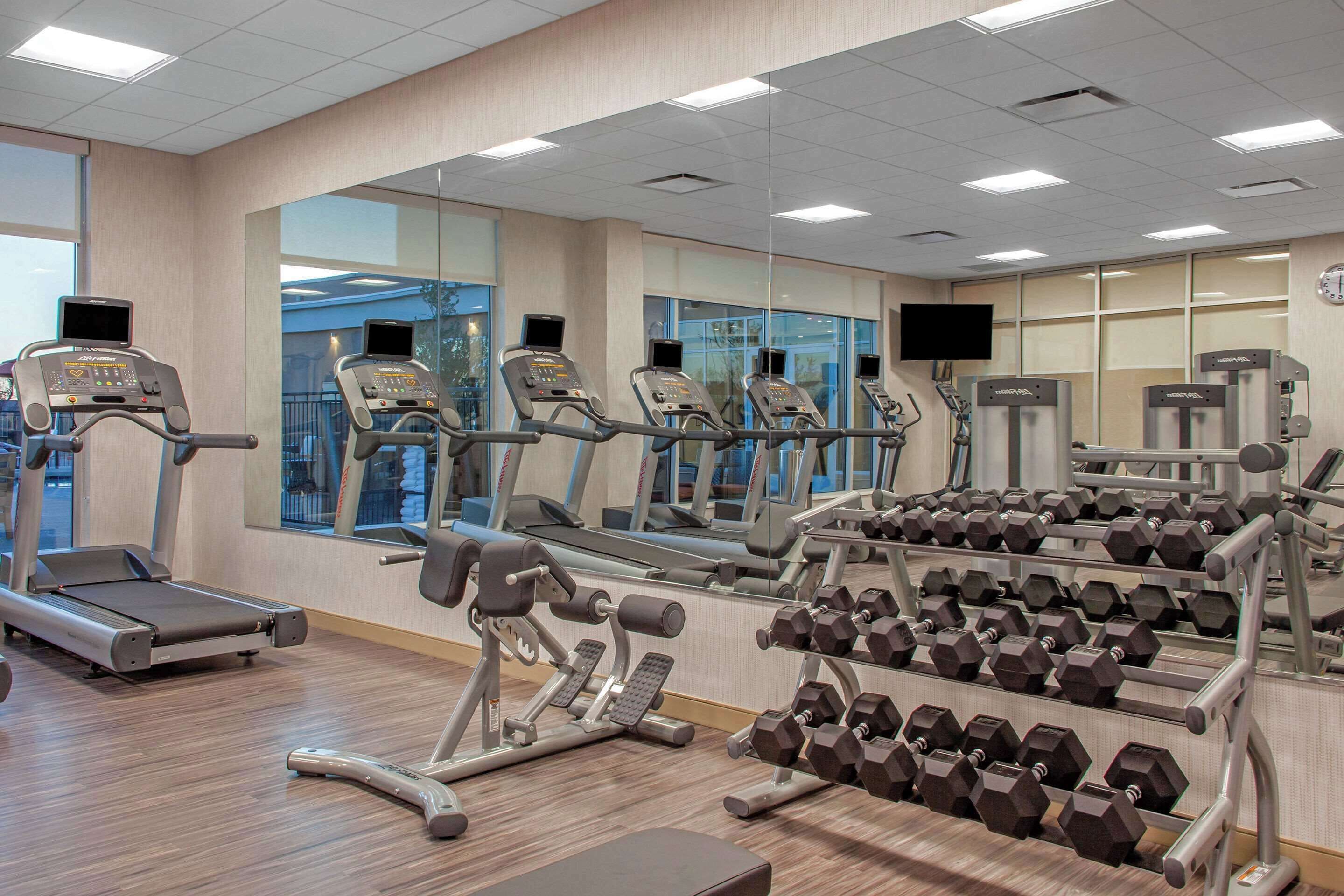 A gym with treadmills, weight machines, and dumbbells.