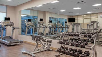 A gym with treadmills, weight machines, and dumbbells.