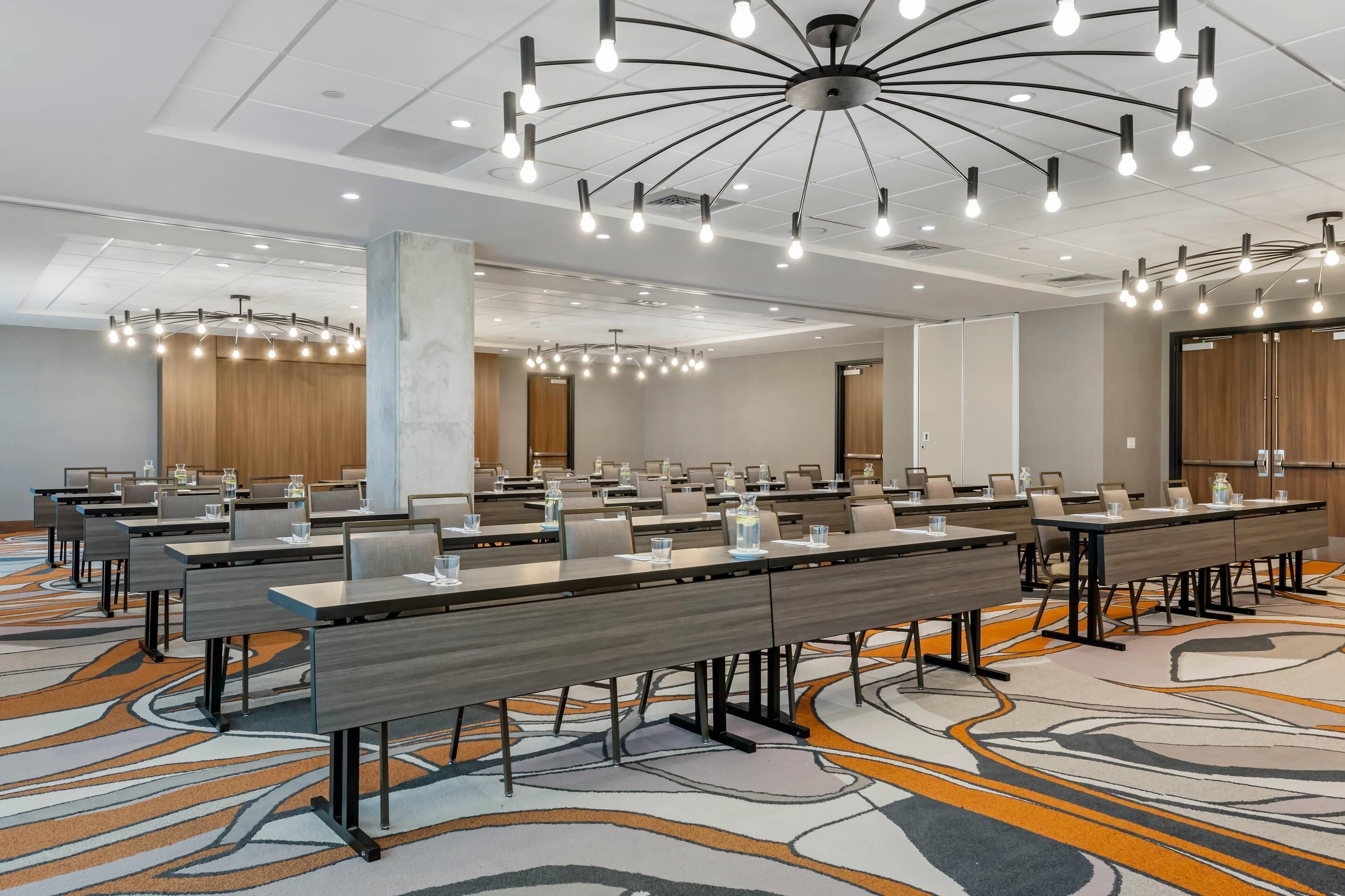 A conference room with long tables, chairs, and modern lighting fixtures.