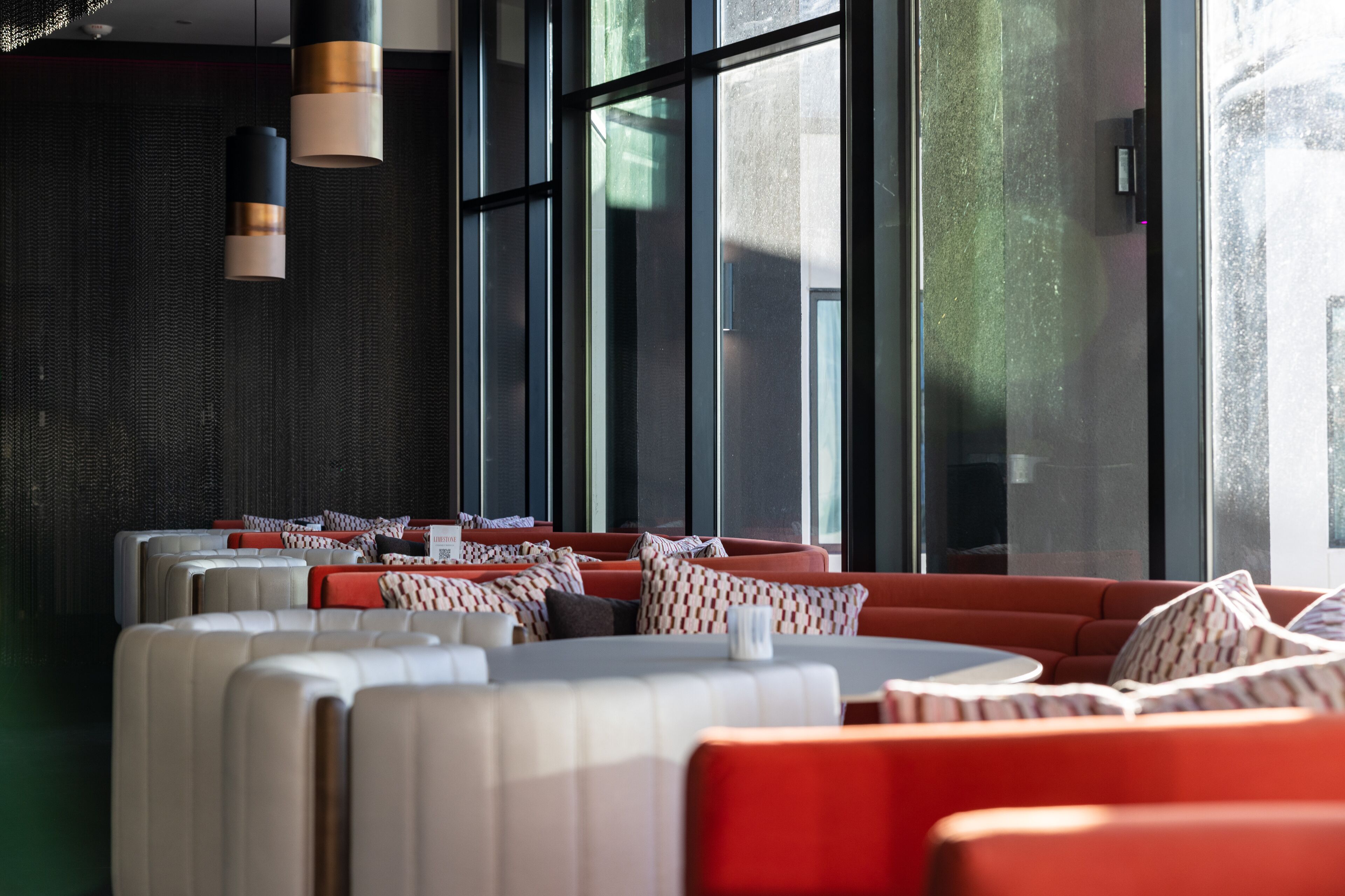 A modern interior with seating areas, large windows, and pendant lighting.