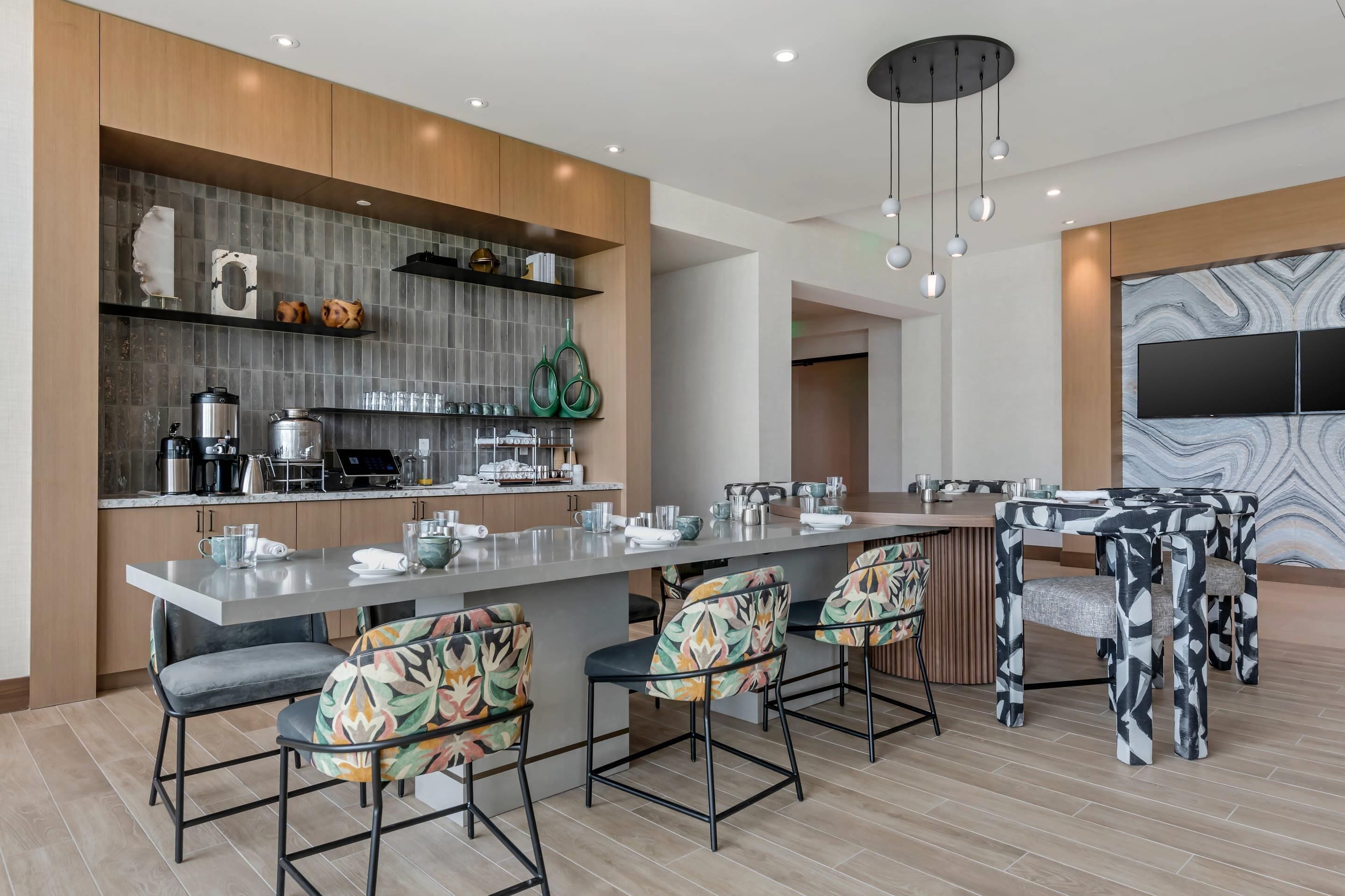 A modern kitchen with a central island, bar stools, and a large TV mounted on the wall.