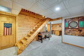 A wooden staircase with a wooden table and dartboards in a room with a high ceiling and wooden walls. - Alexandria Cabin w/ Patio, Grill & Deck (Alexandria)