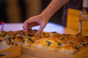 A tray of baked goods, possibly bread or pastries, with a hand reaching for one. - Tugende House (Kigali)