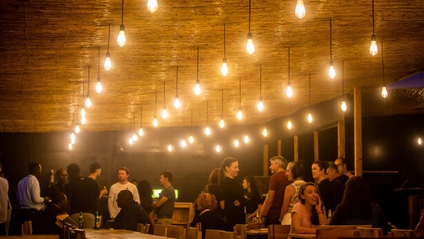 Un espace intérieur bondé, avec des ampoules suspendues, des murs en bois et des tables.