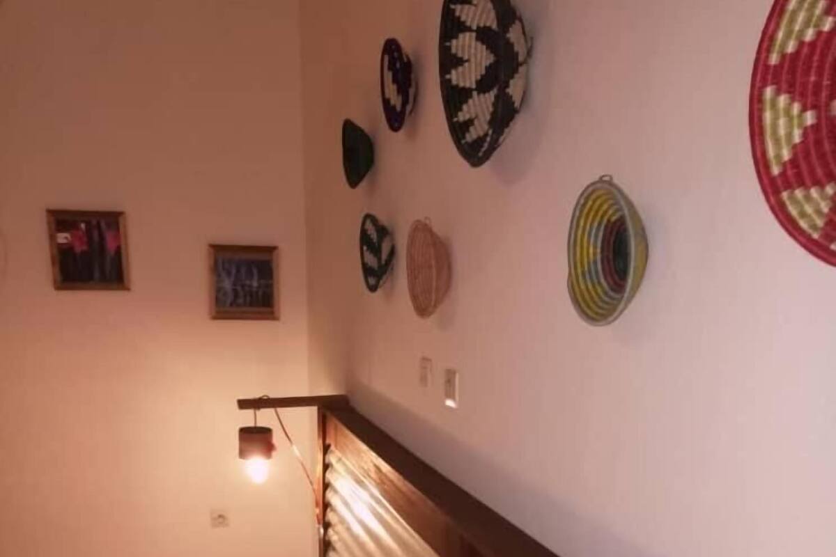 Un dormitorio con cama, cabecera de madera y pared decorada con cestas tejidas.