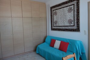 Une pièce avec un canapé de couleur turquoise, une tapisserie à motifs et une armoire en bois.