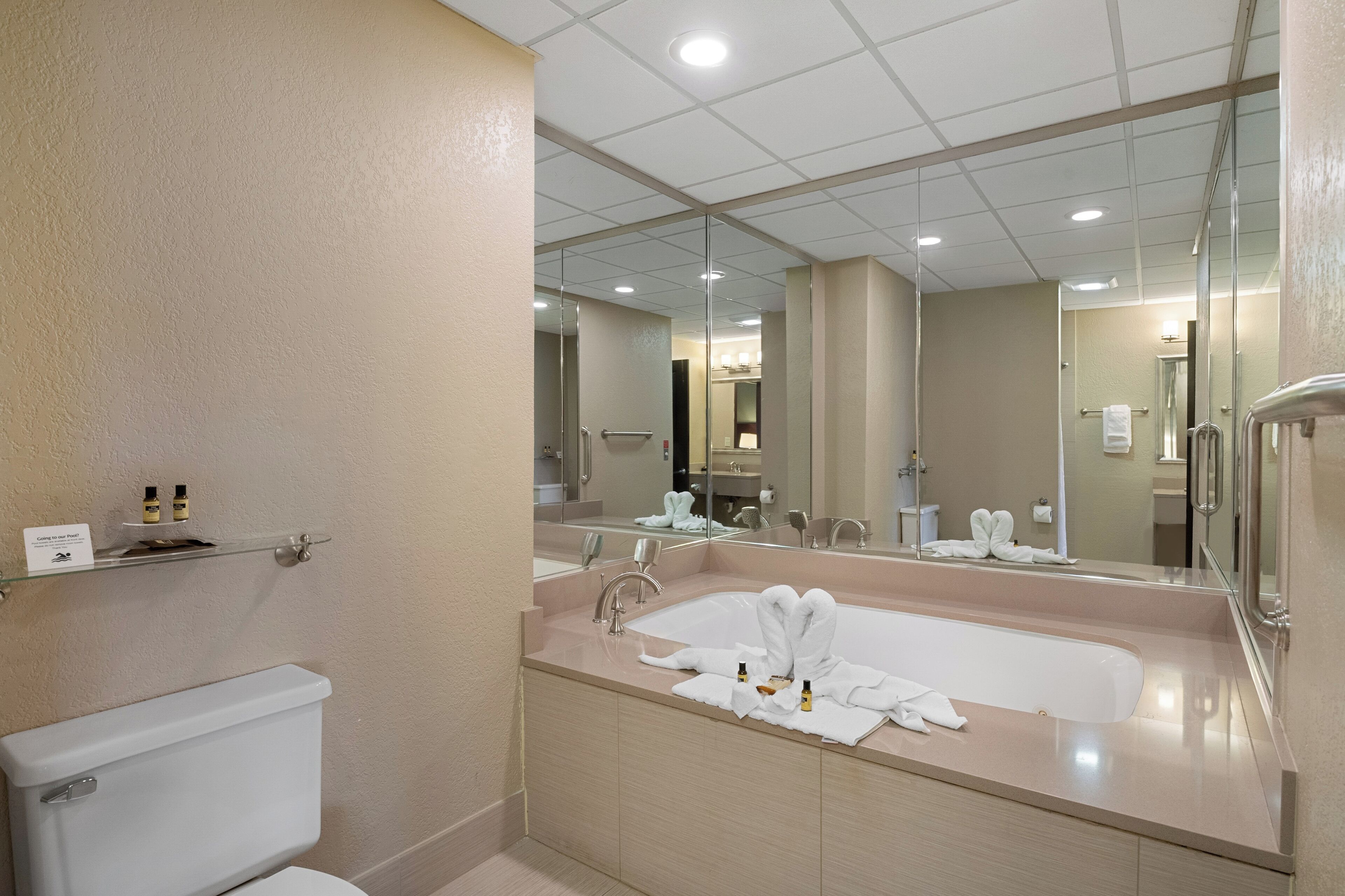Ein modernes Badezimmer mit einem großen Spiegel, einer Badewanne und einer Toilette.
