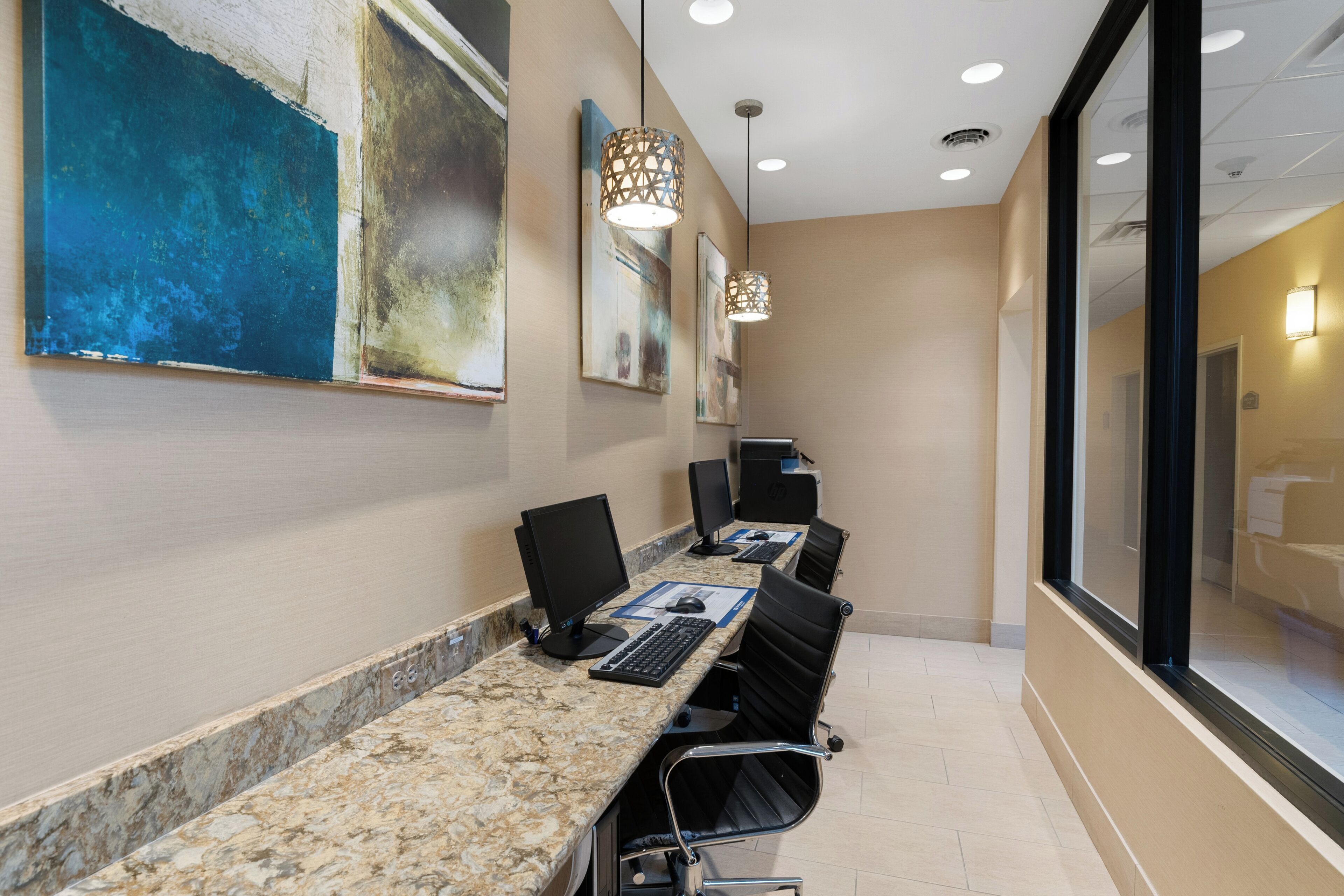 A conference room with a marble table, black chairs, and artwork on the walls.