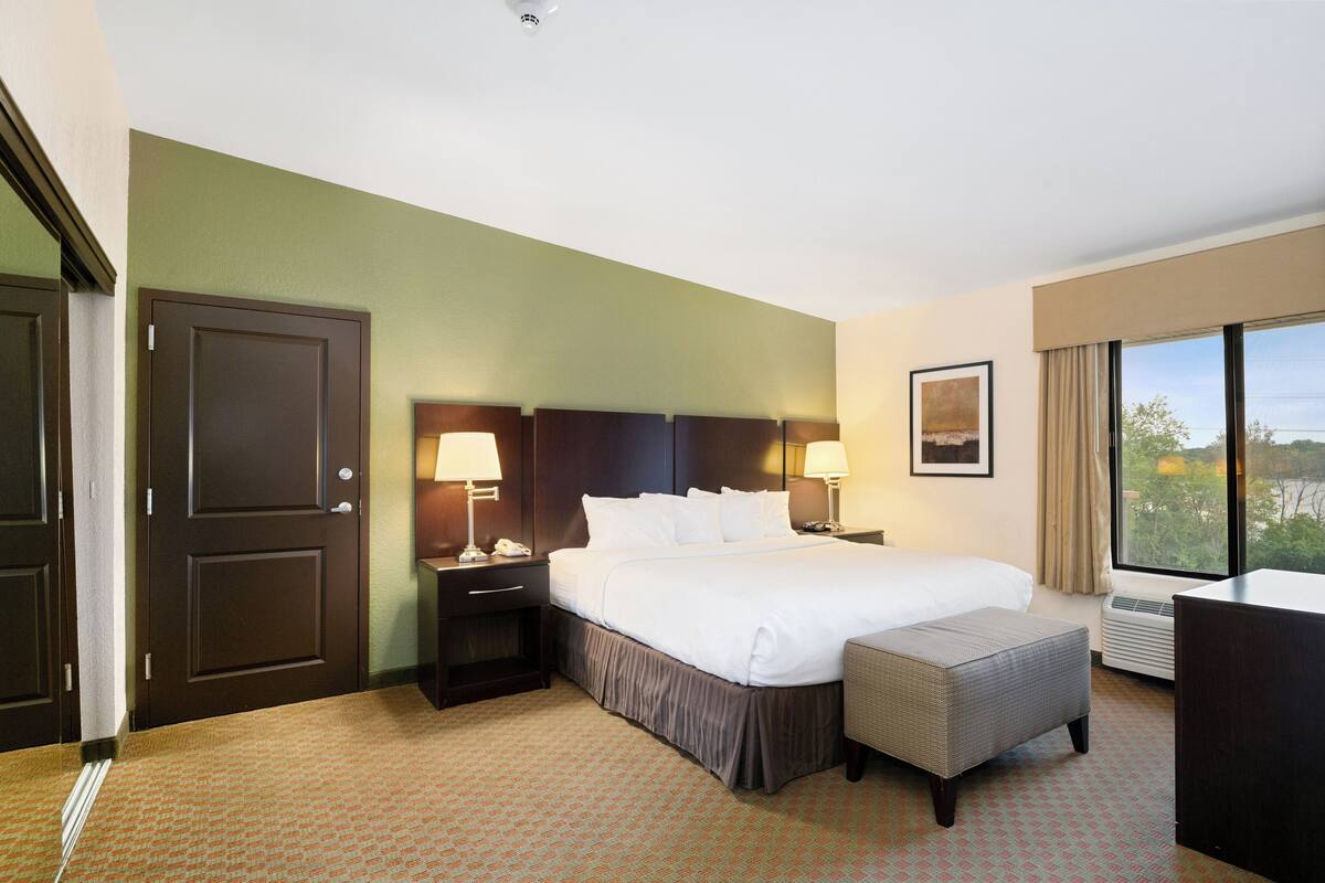 A hotel room with a large bed, bedside lamps, a desk, and a window with a view.