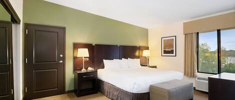 A hotel room with a large bed, bedside lamps, a desk, and a window with a view.