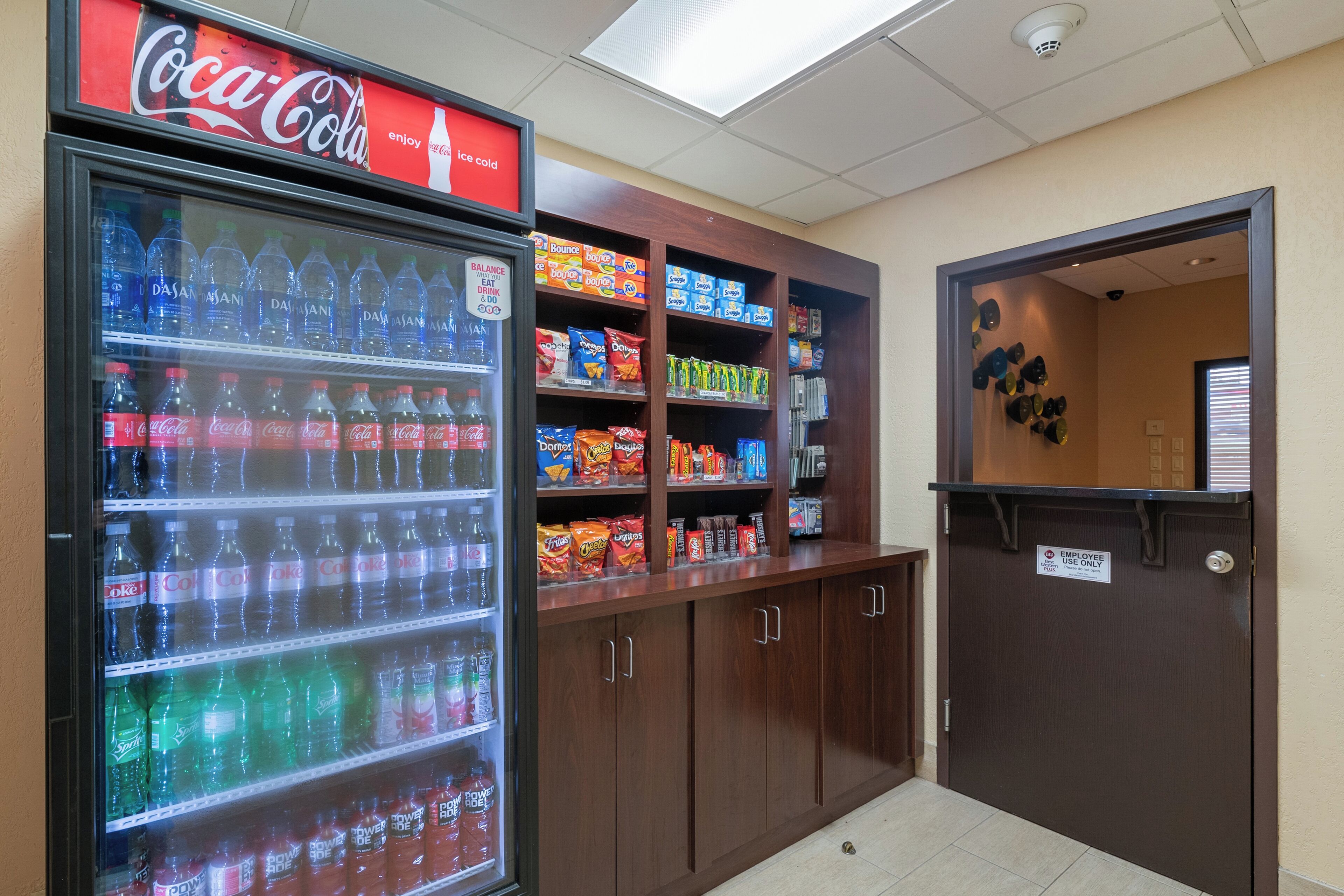 Ein Getränkeautomat mit verschiedenen Getränken und Snacks, ein Coca-Cola-Schild und eine Holzeinrichtung mit Snackregalen.