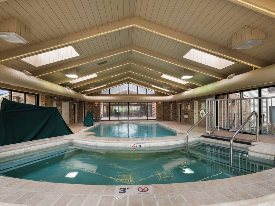 An indoor swimming pool with a 3ft depth limit, surrounded by brick walls and large windows.