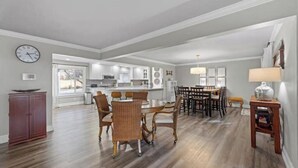A spacious living area with a dining table and chairs, a kitchen in the background, and a clock on the wall. - 3 King Suites · Hot Tub · Fireplace, 10 minutes to Walla Walla (College Place)