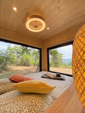 A room with wooden walls and ceiling, large windows, and a bed with patterned bedding. - La Bastide Provençale - Terre D'ocre & de Lavande (Viens)