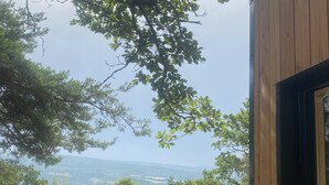 A view from a wooden-framed window overlooking a landscape with trees and distant hills. - La Bastide Provençale - Terre D'ocre & de Lavande (Viens)