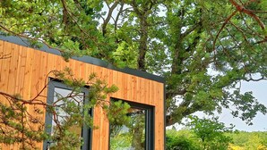 A modern wooden cabin with a large window and a door, surrounded by lush greenery. - La Bastide Provençale - Terre D'ocre & de Lavande (Viens)