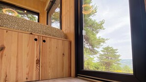 A room with a woven rug, wooden cabinets, and a large window offering a view of trees and hills. - La Bastide Provençale - Terre D'ocre & de Lavande (Viens)
