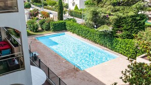 A rectangular swimming pool with a tiled deck, surrounded by lush greenery and residential buildings. - Flat with swimming pool close to the sea (Cagnes-sur-Mer)