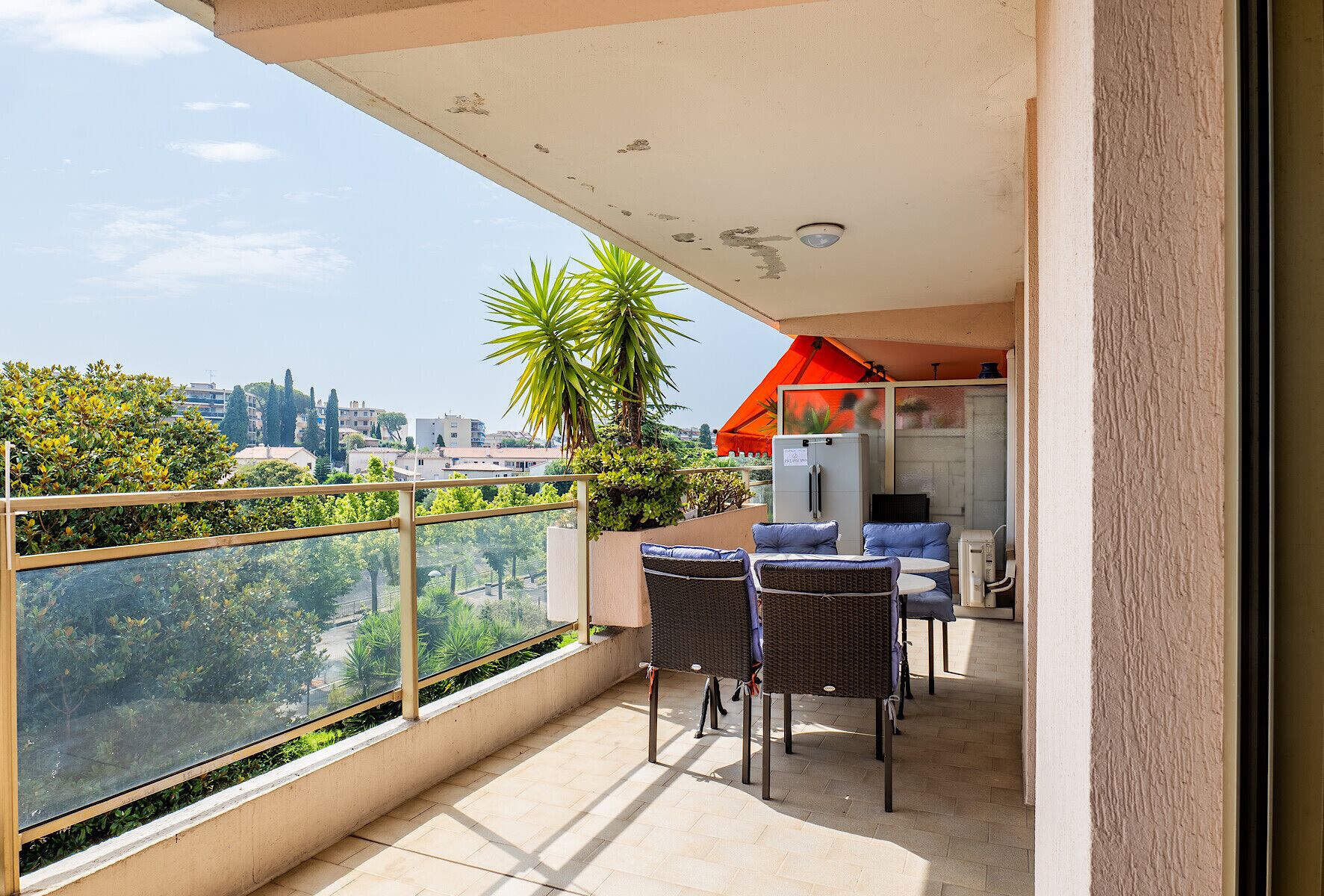 Un balcón con vistas a la ciudad, un refrigerador y mobiliario exterior.
