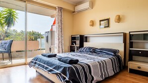 A bedroom with a bed, a chair, a wardrobe, and a sliding glass door leading to an outdoor area. - Flat with swimming pool close to the sea (Cagnes-sur-Mer)