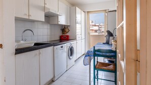 A compact kitchen with a washing machine, a sink, and a window overlooking a cityscape. - Flat with swimming pool close to the sea (Cagnes-sur-Mer)