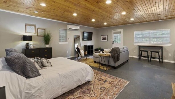 Ein modernes Schlafzimmer mit einem großen Bett, einer Couch, einem Fernseher und einem Kamin.