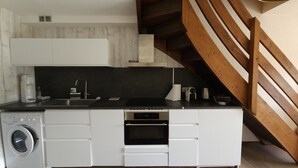 A compact kitchen with a washing machine, a coffee maker, and a microwave.