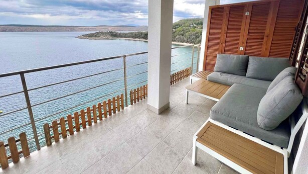 Ein Balkon mit Blick auf das Meer, ein Sofa und ein Tisch aus Holz.