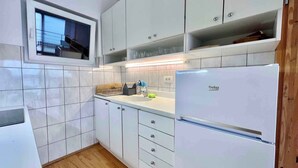 Eine moderne Küche mit weißen Schränken, einem integrierten Fenster und einem Kühlschrank.