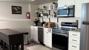 Una cocina moderna con armarios blancos, electrodomésticos de acero inoxidable y una mesa de madera.