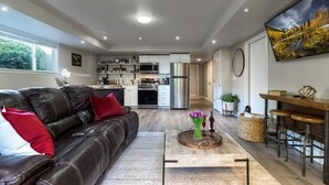 Una sala de estar moderna con un sofá de cuero, una mesa de centro con flores y una cocina al fondo.
