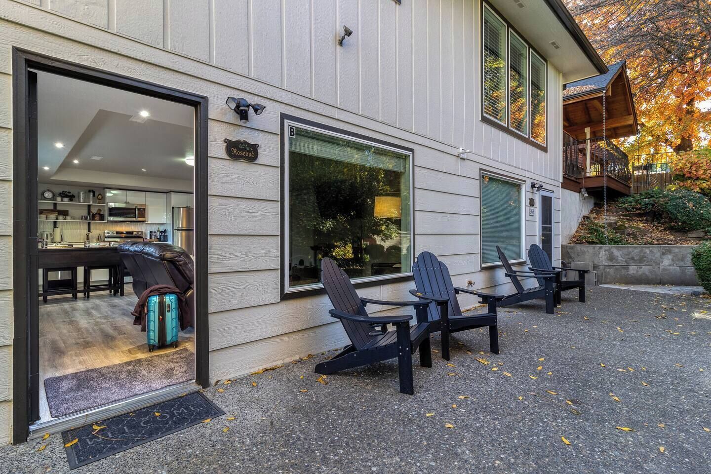 Une maison moderne dotée d’une cuisine ouverte, d’un espace extérieur aménagé avec des chaises et d’un escalier menant à un balcon.